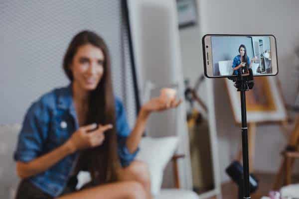 Blogger of caucasian woman with review product and talking camera live recording video on social network at home. Online merchants selling cosmetics on social media via mobile phones.