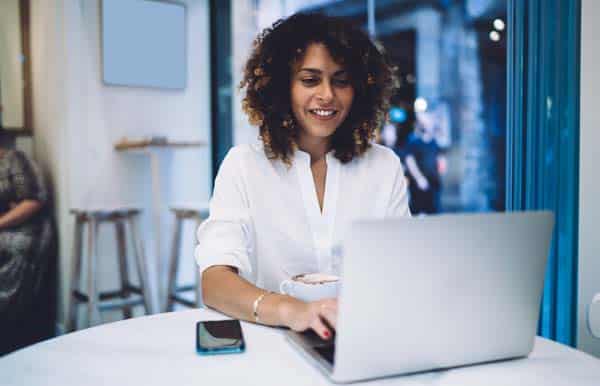 Happy Caucaisan freelancer in smart casual clothing using laptop technology for searching web info,cheerful female programmer working remotely on netbook installing application while browsing wireless